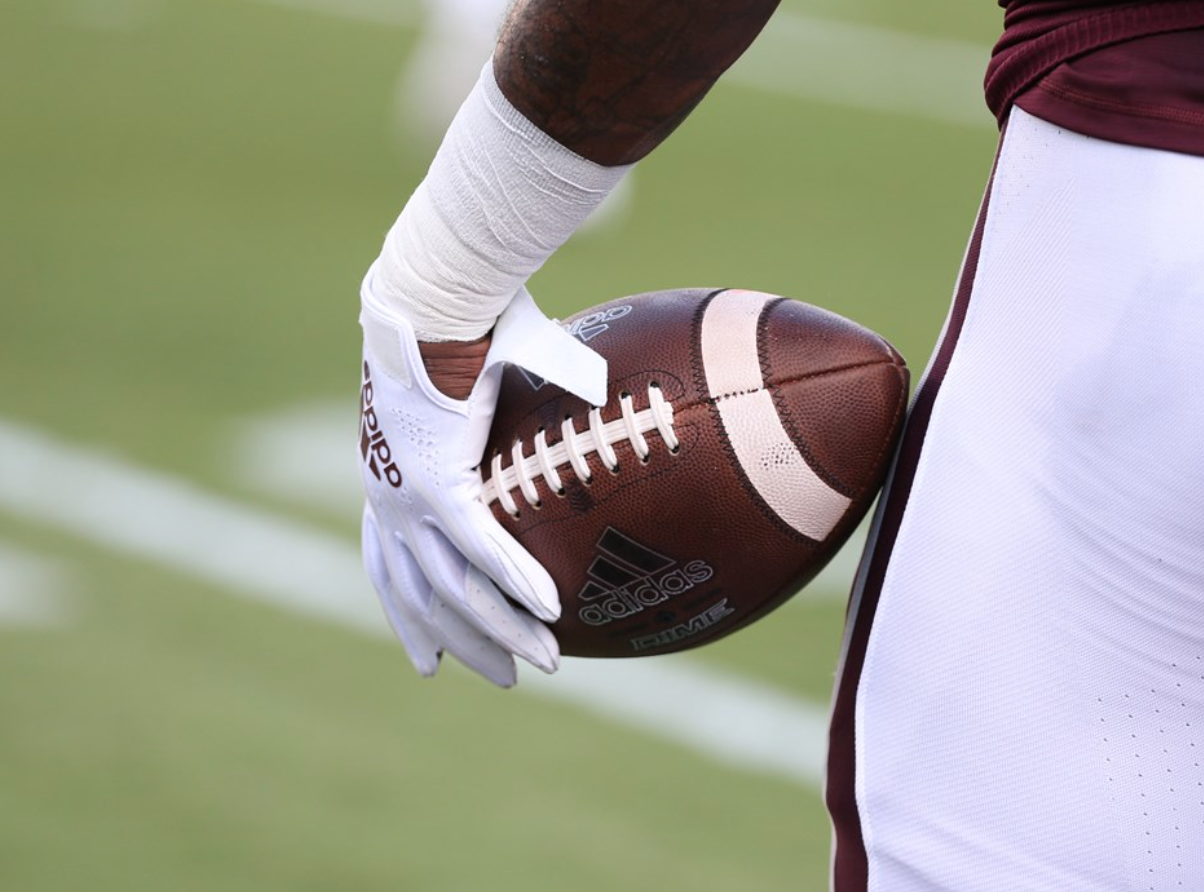A football being held by a Mississippi State football player.